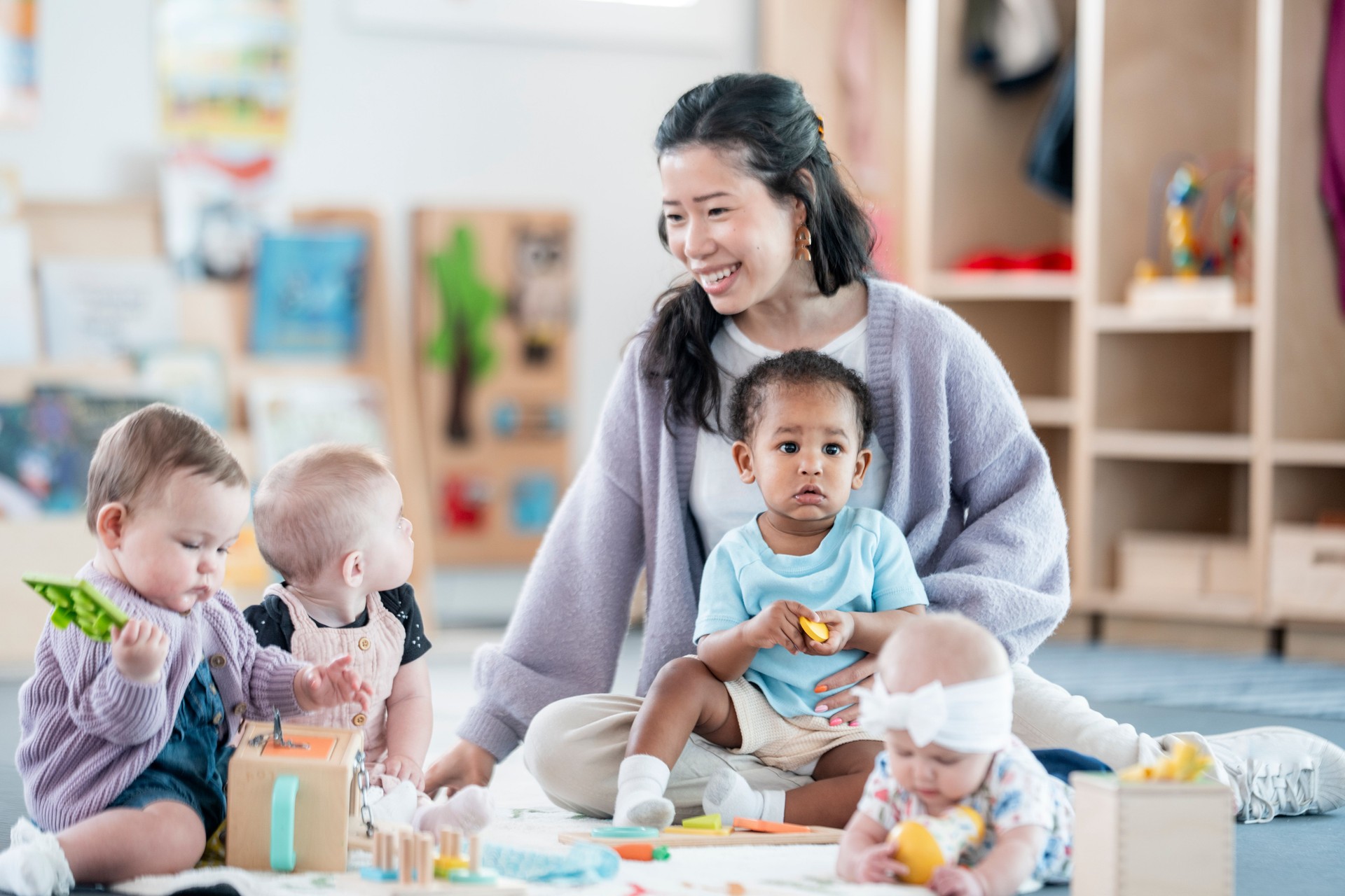 Childcare Teacher Engaged with Multicultural Infants in a Bright Classroom
