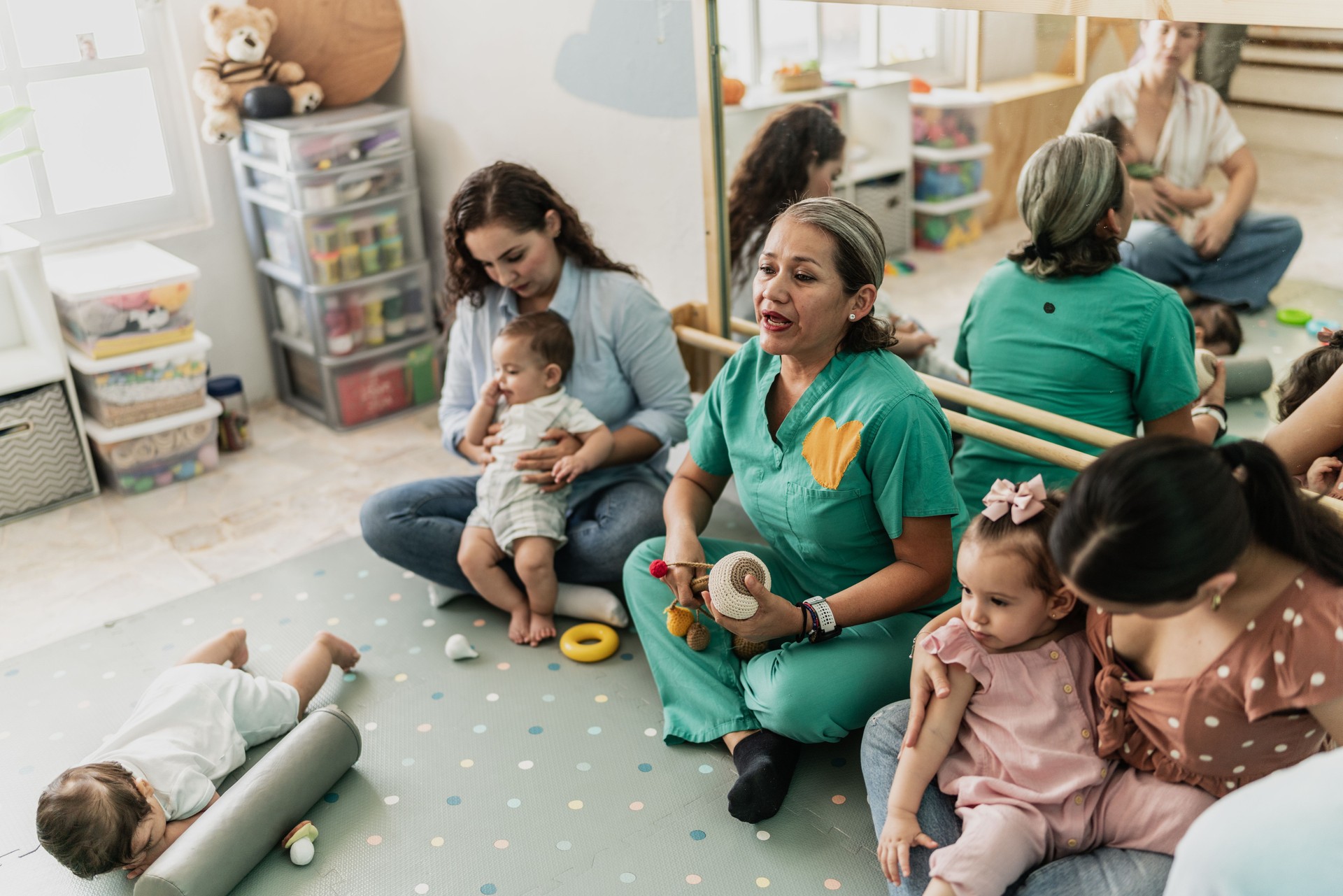 Mature woman teaching mothers how to breastfeed their babies at support group
